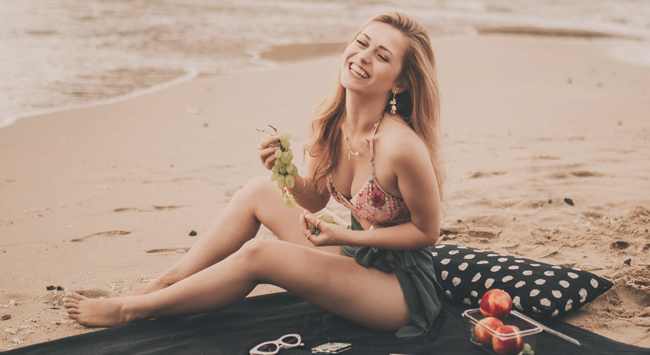 砂浜でピクニックをするビキニを着た女性